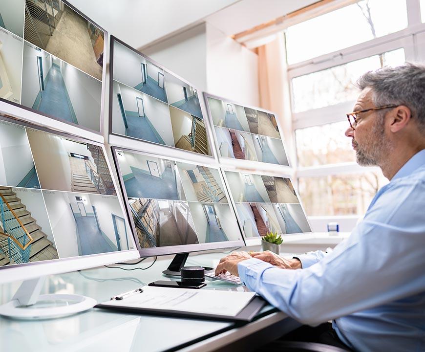 Man Looking at Monitors for Business Security Systems in Alpharetta, Atlanta, Brookhaven, Canton, Kennesaw, Sandy Springs